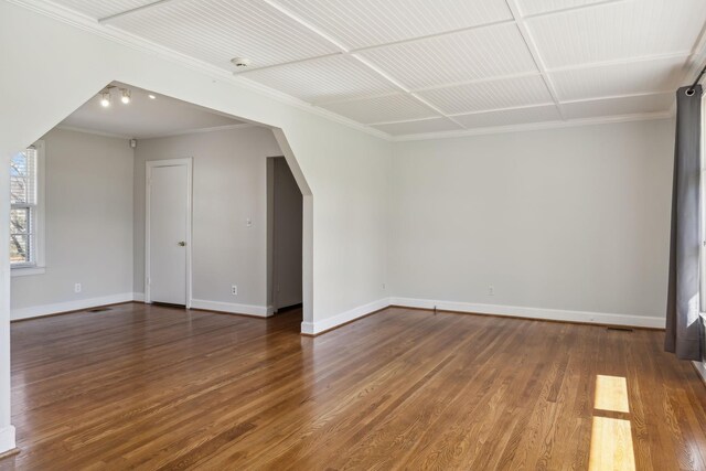 additional living space with baseboards, arched walkways, and wood finished floors