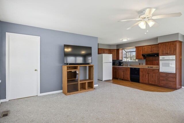 kitchen featuring white appliances, a sink, visible vents, and light colored carpet