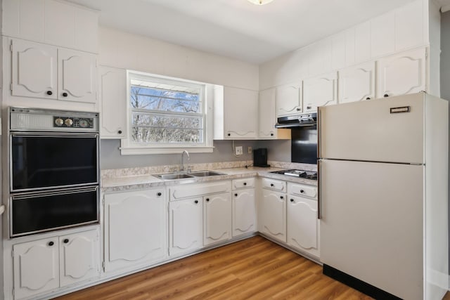 kitchen featuring oven, a sink, white cabinetry, freestanding refrigerator, and a warming drawer