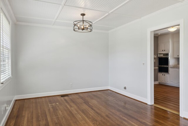 empty room with baseboards, an inviting chandelier, and wood finished floors