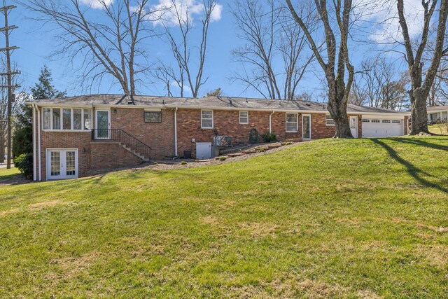 view of front of home featuring a garage, a front yard, french doors, and brick siding