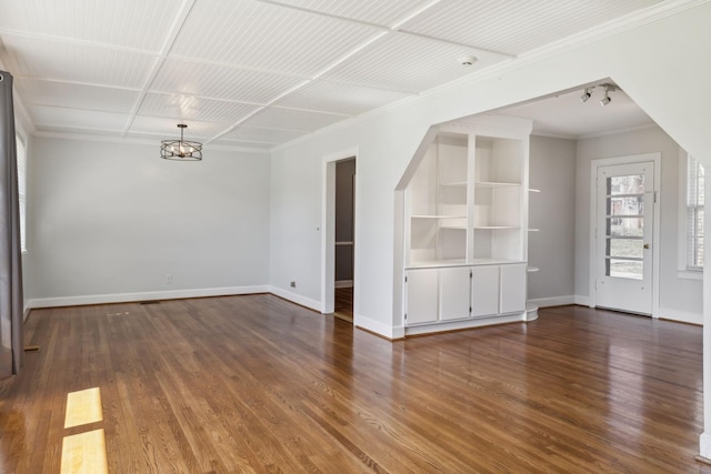 unfurnished living room featuring crown molding, a notable chandelier, wood finished floors, and baseboards