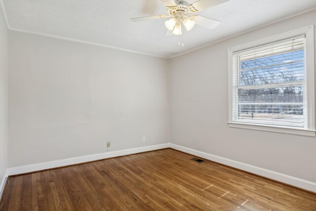 empty room with ceiling fan, wood finished floors, visible vents, and baseboards