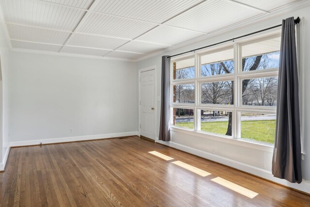 spare room with baseboards and wood finished floors