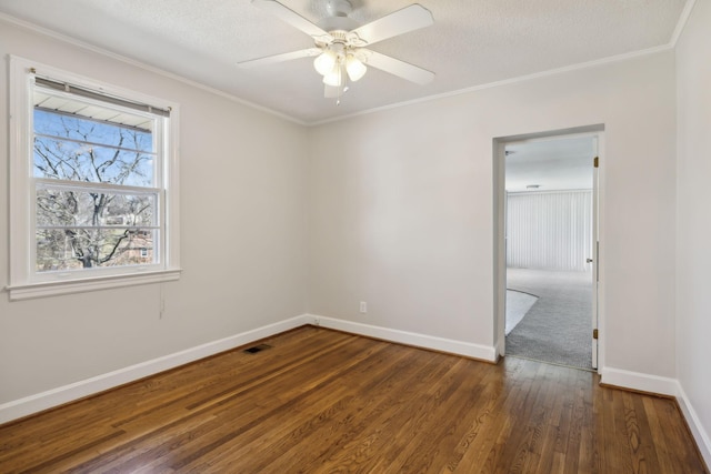 unfurnished room with visible vents, dark wood finished floors, and ornamental molding