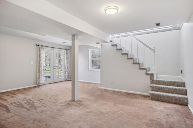 below grade area featuring carpet floors, baseboards, stairway, and french doors