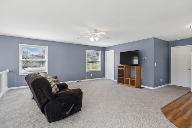 carpeted living room with a ceiling fan and baseboards