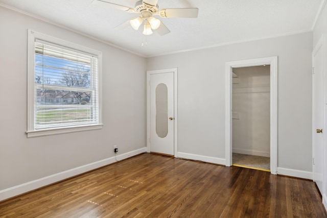 unfurnished bedroom with a closet, crown molding, baseboards, and wood finished floors