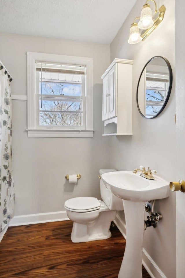 bathroom featuring curtained shower, wood finished floors, toilet, and baseboards