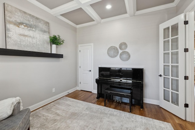 sitting room featuring coffered ceiling, wood finished floors, baseboards, beam ceiling, and crown molding