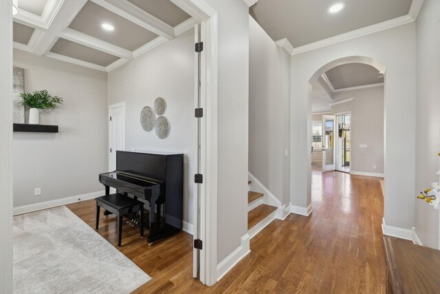 hallway featuring arched walkways, coffered ceiling, baseboards, and wood finished floors