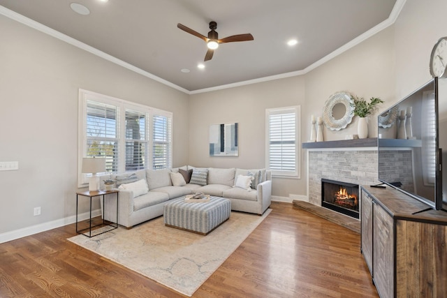 living room with a brick fireplace, baseboards, wood finished floors, and ornamental molding