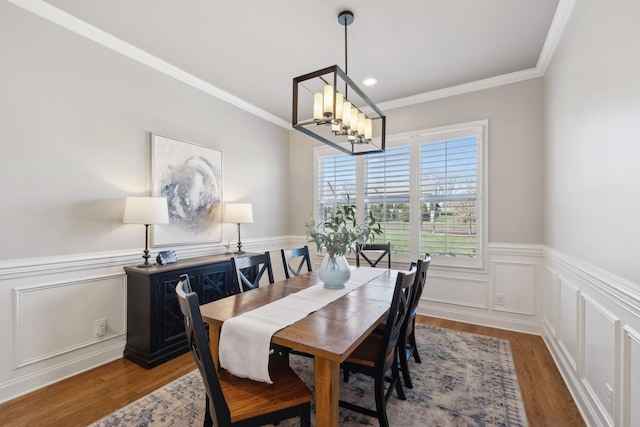 dining area with ornamental molding, a wainscoted wall, and wood finished floors