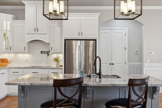 kitchen featuring ornamental molding, white cabinetry, freestanding refrigerator, and black electric cooktop