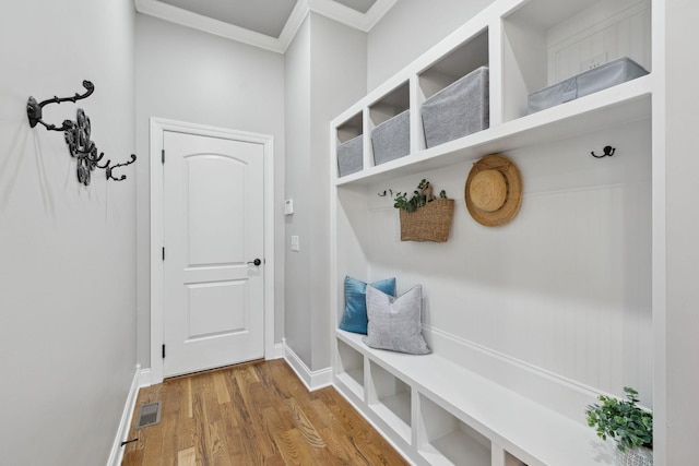 mudroom featuring baseboards, visible vents, wood finished floors, and ornamental molding