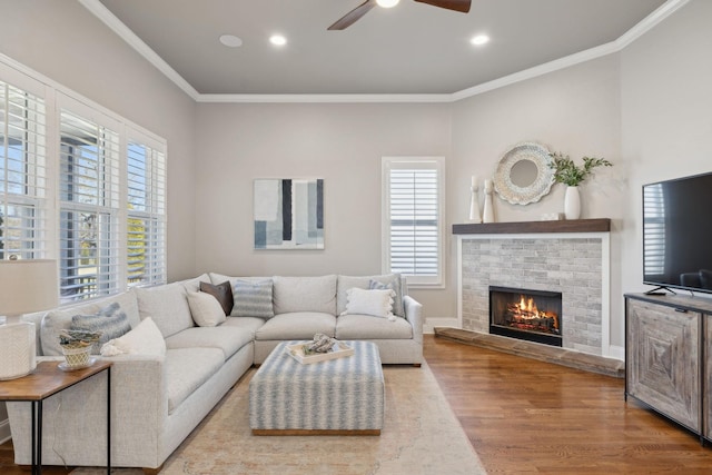 living room featuring a fireplace, crown molding, recessed lighting, wood finished floors, and baseboards