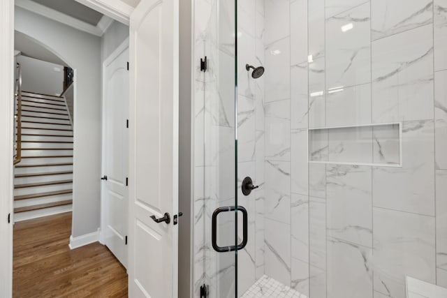 full bath with wood finished floors, a marble finish shower, and crown molding