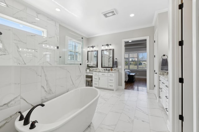 full bath with marble finish floor, vanity, crown molding, and a soaking tub