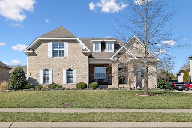 view of front of house with stone siding, brick siding, a front lawn, and roof with shingles