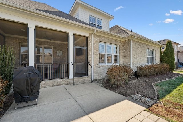 entrance to property with a shingled roof and brick siding