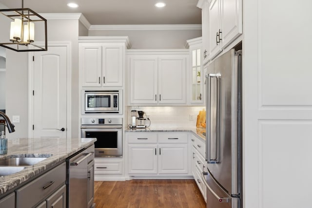 kitchen with stainless steel appliances, decorative backsplash, dark wood-type flooring, white cabinetry, and a sink