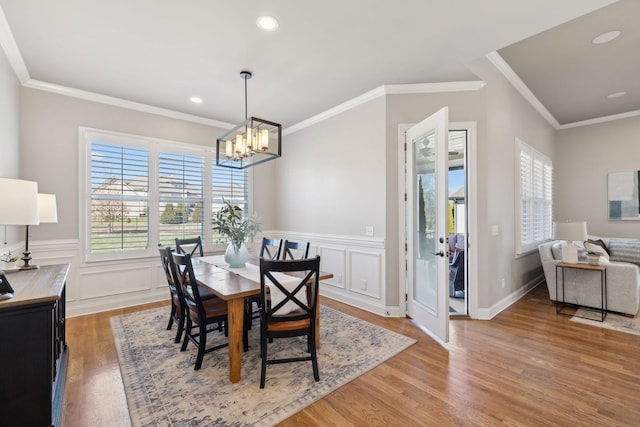 dining room featuring a healthy amount of sunlight, crown molding, a decorative wall, and wood finished floors