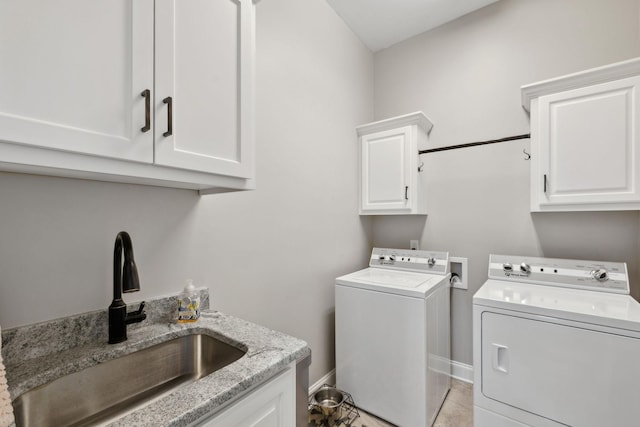 washroom with baseboards, a sink, cabinet space, and washer and dryer