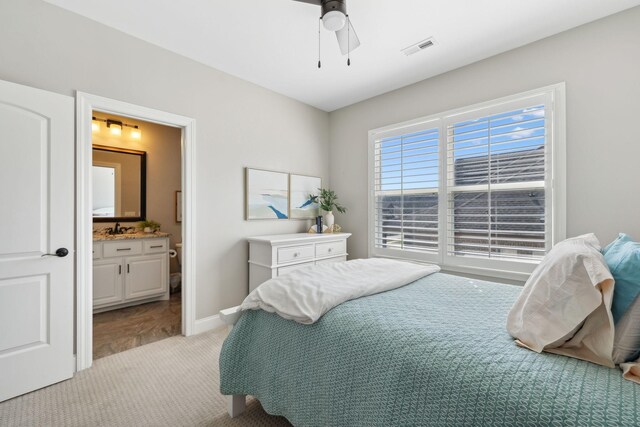 bedroom featuring connected bathroom, light carpet, a ceiling fan, visible vents, and baseboards