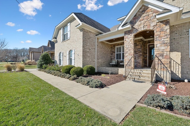 view of side of home with stone siding, brick siding, and a lawn