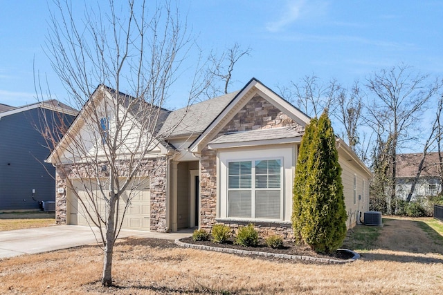 view of front of property featuring an attached garage, stone siding, driveway, and central AC