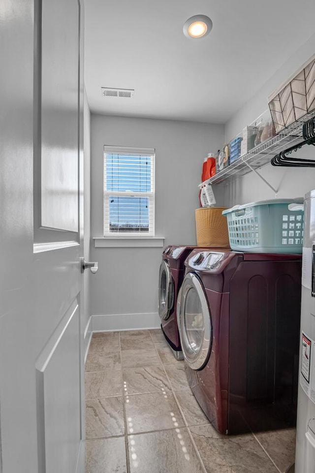 laundry area featuring washing machine and clothes dryer, visible vents, electric water heater, laundry area, and baseboards