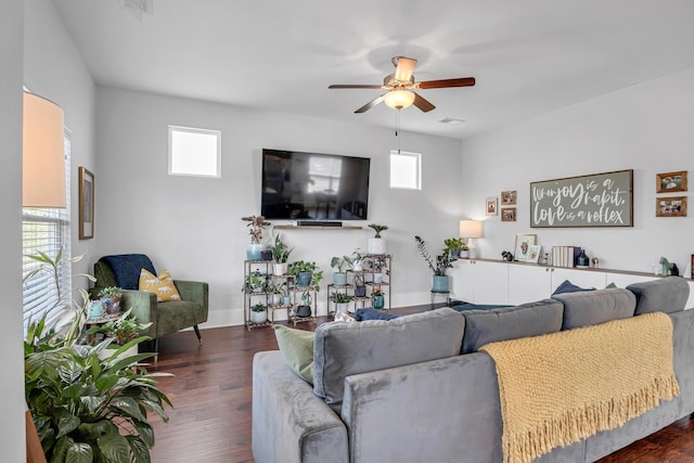 living area featuring ceiling fan, plenty of natural light, dark wood finished floors, and baseboards