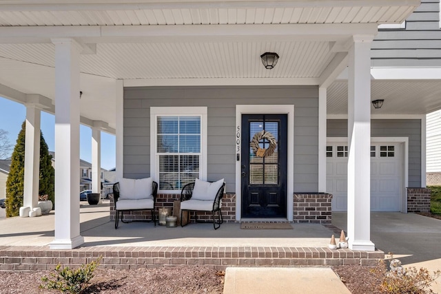 view of exterior entry with driveway, covered porch, a garage, and brick siding