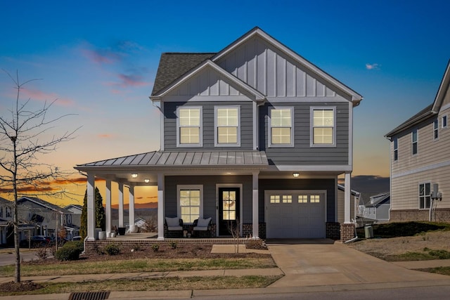 view of front of house with brick siding, covered porch, board and batten siding, a standing seam roof, and driveway