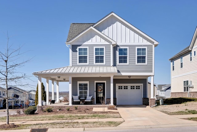 view of front of home featuring driveway, a standing seam roof, a porch, board and batten siding, and brick siding