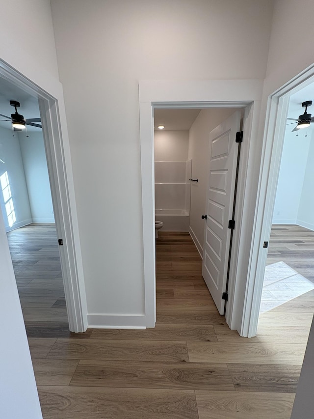 hall with baseboards and wood finished floors