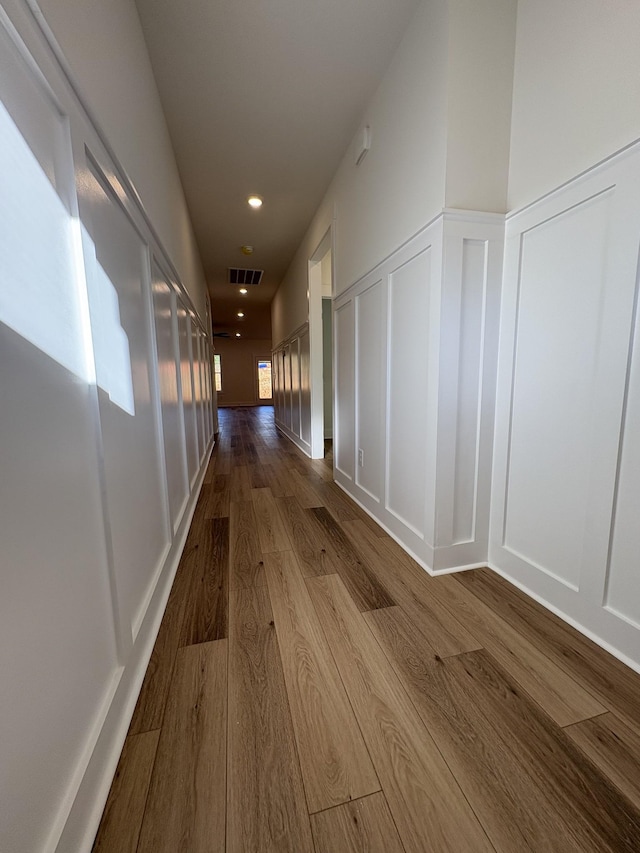 corridor featuring recessed lighting, a wainscoted wall, a decorative wall, visible vents, and dark wood finished floors