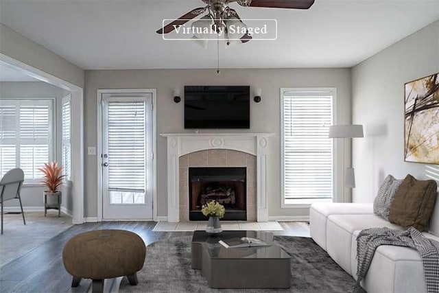 living area featuring ceiling fan, a fireplace, wood finished floors, and baseboards