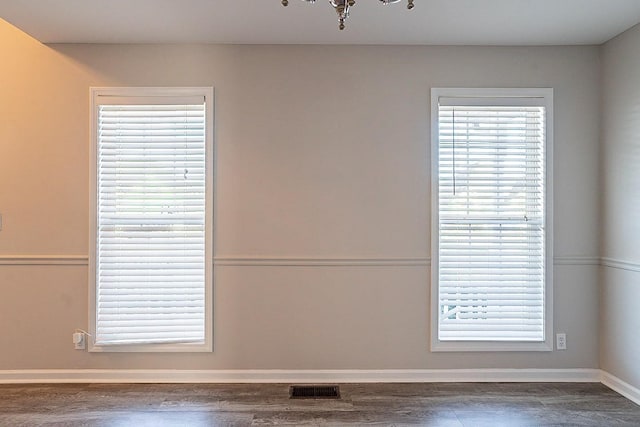 unfurnished room featuring baseboards, visible vents, and wood finished floors