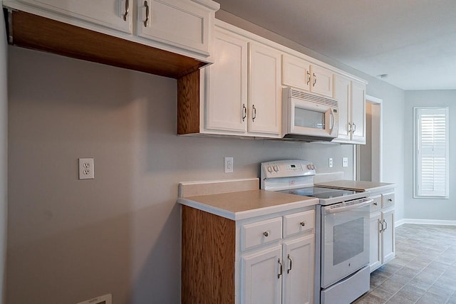 kitchen with light countertops, white appliances, white cabinetry, and baseboards