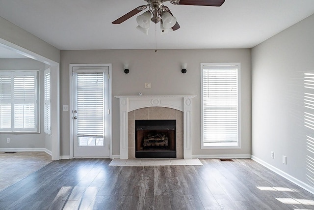 unfurnished living room featuring a fireplace, wood finished floors, visible vents, and baseboards