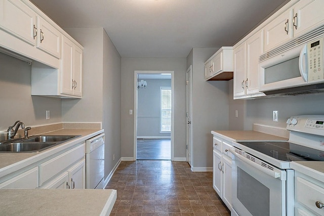 kitchen with light countertops, white appliances, white cabinets, and a sink