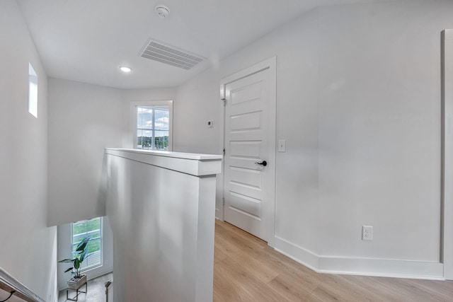 interior space with light wood-style flooring, plenty of natural light, an upstairs landing, and visible vents