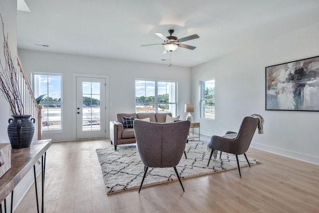 living area with light wood-type flooring, ceiling fan, and baseboards