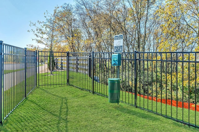 view of gate with fence and a lawn