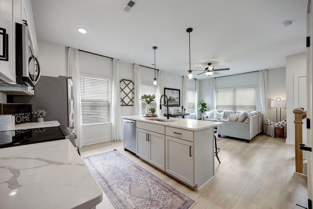 kitchen with visible vents, dishwasher, light wood-style flooring, decorative light fixtures, and a sink