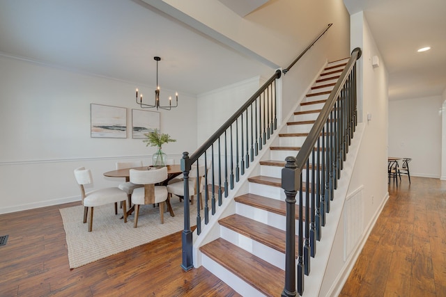 stairway featuring visible vents, ornamental molding, a chandelier, baseboards, and hardwood / wood-style flooring