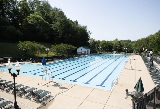 pool with a patio area and fence