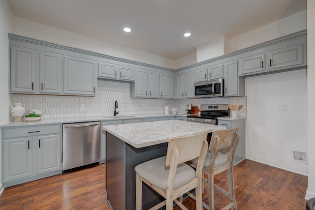 kitchen with appliances with stainless steel finishes, a breakfast bar, gray cabinets, and a sink