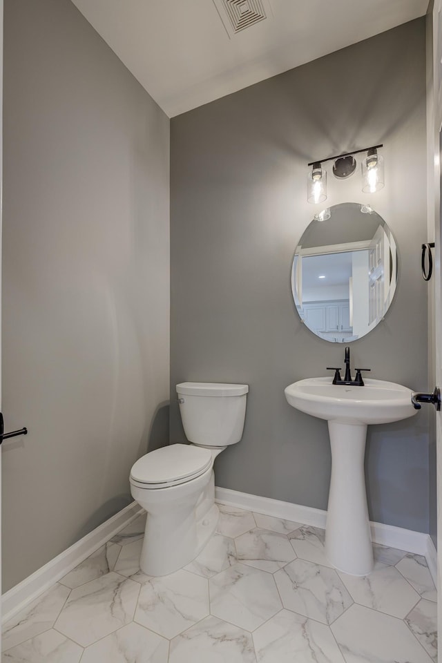 half bath with toilet, marble finish floor, visible vents, and baseboards